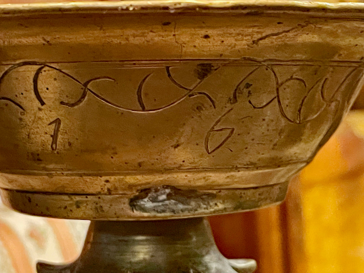 Engraved numerals and foliage on the bronze drip bowl, detail