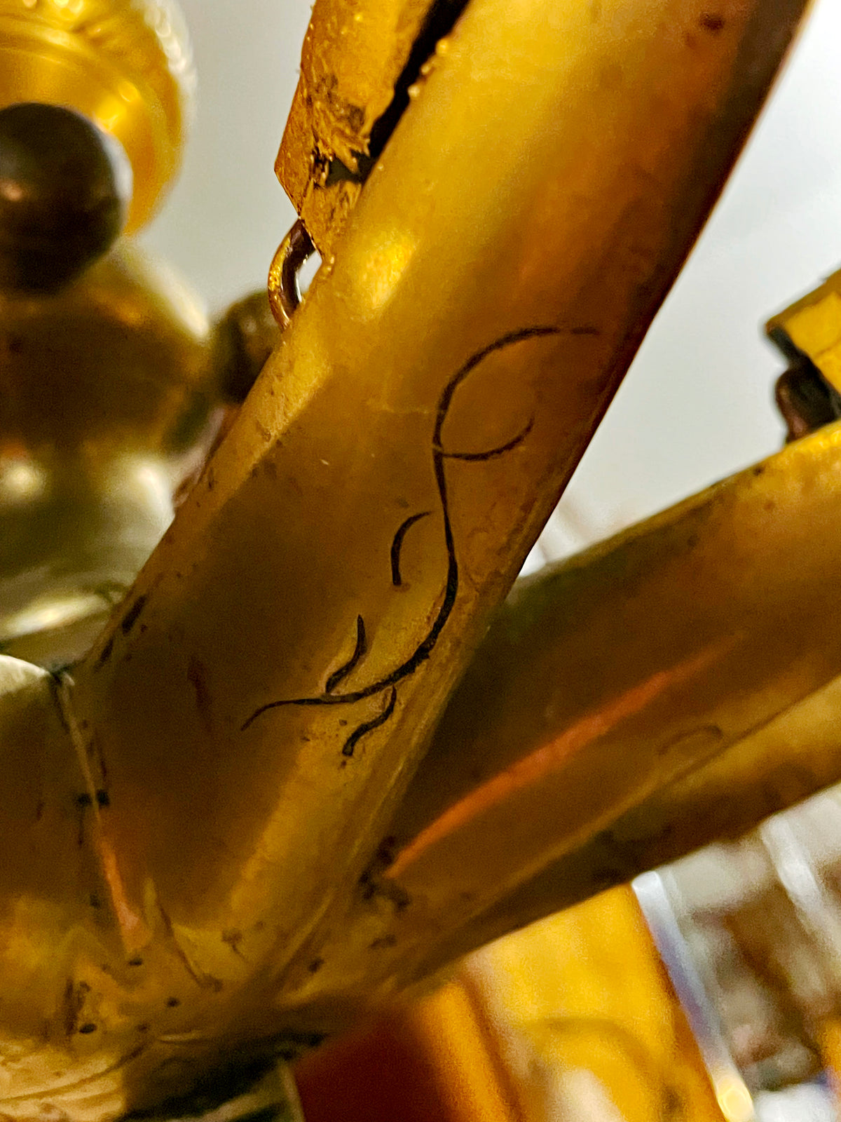 Close-up of engraved scroll decoration on a bronze arm of the Sabbath lamp