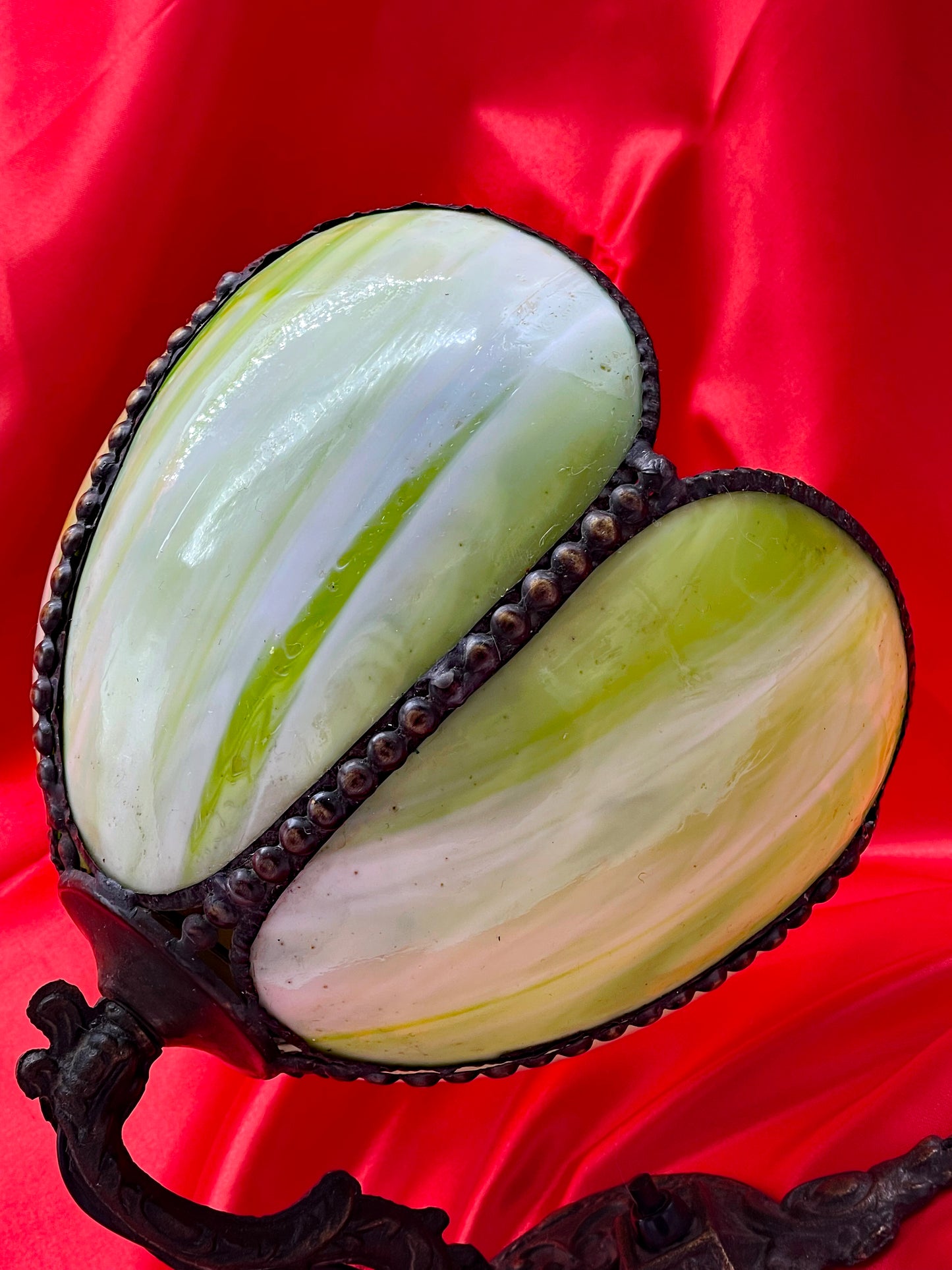 Close-up of the marbled green and white slag glass petals of the Art Nouveau water lily wall sconce