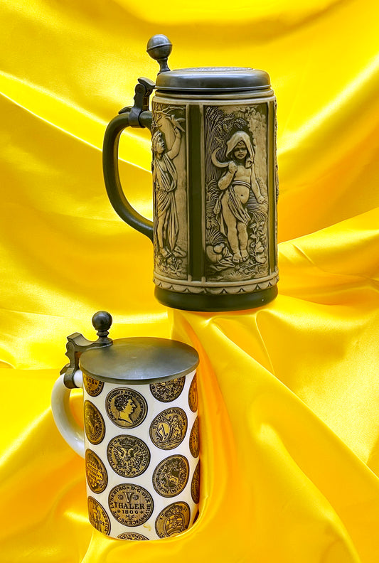 Pair of antique German beer steins with pewter lids on yellow satin, relief stein and gilt Thaler coin stein