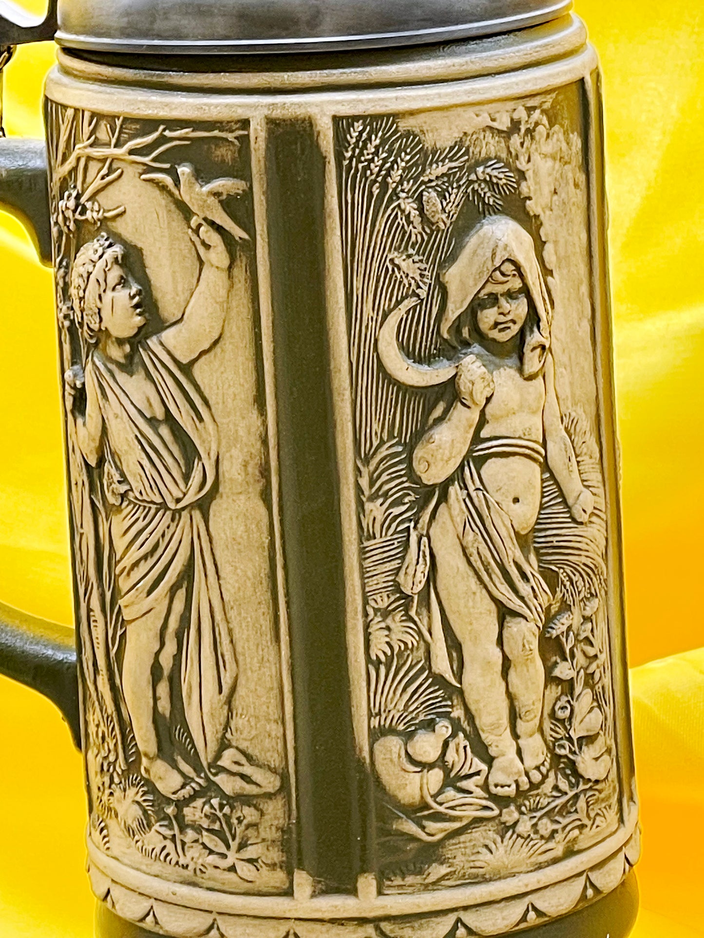 Close-up of relief stein figures harvesting grapes in ivory and olive glaze