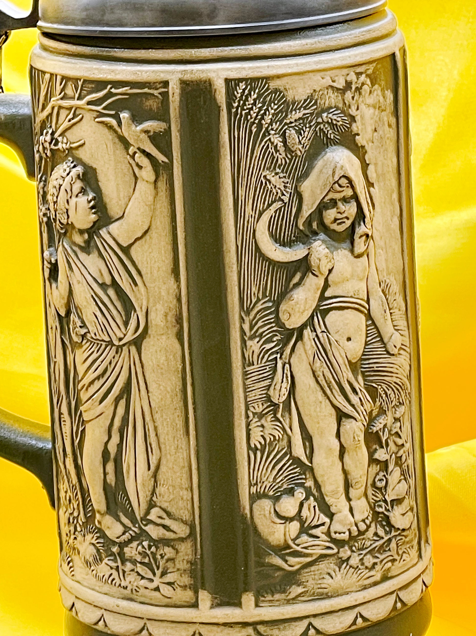 Close-up of relief stein figures harvesting grapes in ivory and olive glaze