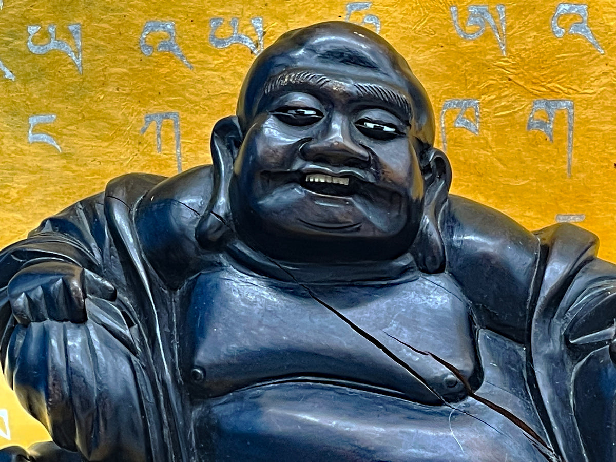 Close up of the laughing Buddha face with inlaid bone and horn eyes