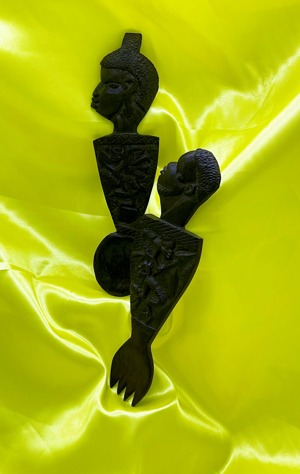 Full view of the antique ebony spoon and fork couple on yellow satin